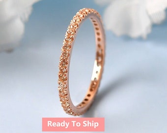 May include: A delicate rose gold band ring with a row of small, clear gemstones encircling the band.  Ready To Ship.