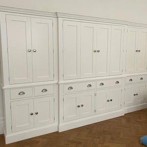 May include: White kitchen cabinet with multiple doors and drawers. The cabinet has a traditional style with simple hardware.