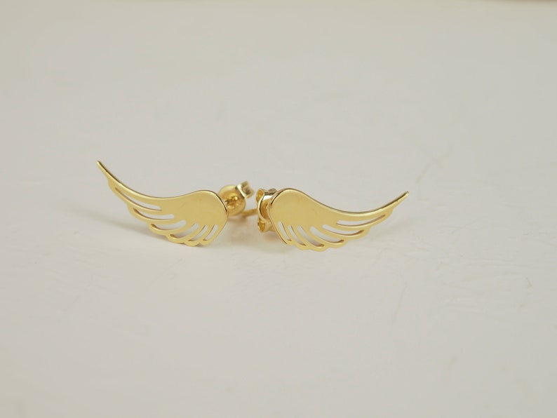 Puede incluir: Un par de pendientes de color dorado con forma de alas de &aacute;ngel. Las alas son delicadas y tienen un dise&ntilde;o recortado.