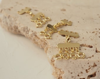 May include: Three gold-toned metal charms with a dangling chain of small rings. The charms are shaped like a cloud with a scalloped edge.