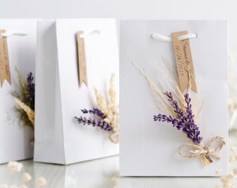 May include: White gift bags with dried lavender and wheat bouquets attached. Each bag has a brown paper tag with the text "Shannon & Justin 10.28.2023".
