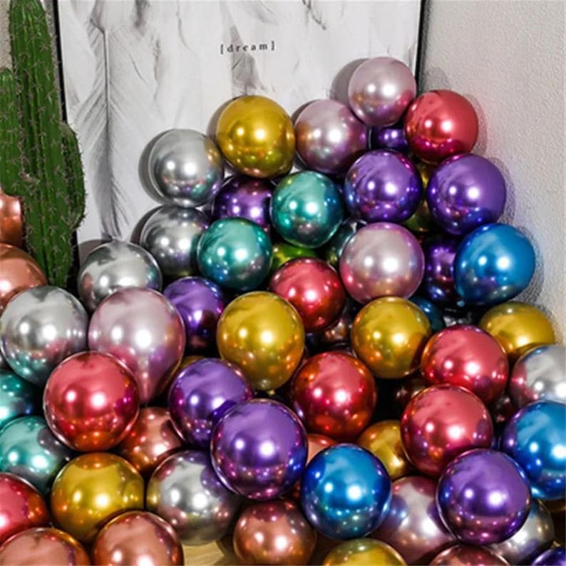 May include: A large pile of colorful metallic balloons. The balloons are shiny and reflect light. They are a variety of colors, including gold, silver, purple, blue, red, and green.