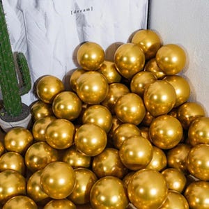 May include: A large pile of gold metallic balloons. The balloons are shiny and reflect light.