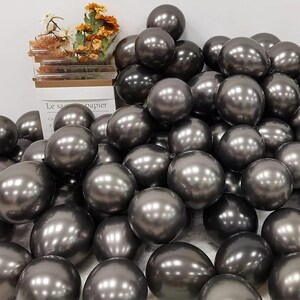 May include: A large group of metallic gray balloons. The balloons are shiny and have a reflective surface.
