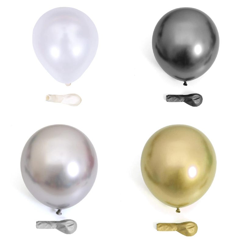May include: Four metallic balloons in silver, gold, black, and white. Each balloon is inflated and tied off with a matching colored ribbon.