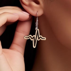 Puede incluir: Pendientes colgantes plateados con un diseño de latido de corazón dorado. Los pendientes tienen un estilo sencillo y elegante, con cierre de gancho. El diseño de latido de corazón es un símbolo popular.