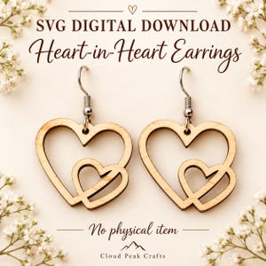 May include: A pair of light-coloured wooden heart-in-heart earrings with silver-toned metal hooks. The text reads: SVG DIGITAL DOWNLOAD, Heart-in-Heart Earrings, No physical item, and Cloud Peak Crafts.