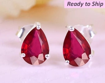 May include: A pair of silver teardrop earrings with red gemstone accents.