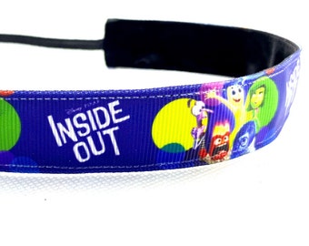 Puede incluir: Una diadema azul con personajes de la película de Disney Pixar "Del revés". La diadema tiene una banda elástica negra y las palabras "INSIDE OUT" en blanco. El diseño incluye imágenes de los personajes Alegría, Tristeza, Ira, Miedo y Asco.