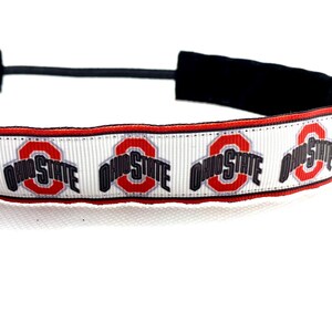 Può includere: Un cerchietto bianco con un elastico nero e un motivo ripetuto del logo dell'Ohio State in rosso, grigio e nero.