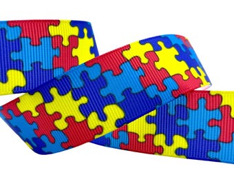 Może przedstawiać: Kolorowa wstążka z wzorem puzzli w kolorze czerwonym, żółtym i niebieskim. Ta wstążka jest idealna do rękodzieła, pakowania prezentów lub dodawania odrobiny świadomości do różnych projektów. Wzór jest efektowny i symboliczny.