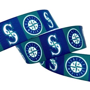May include: Ribbon featuring the Seattle Mariners logo. The ribbon has a repeating pattern of the team's logo and the letter "S" in white against a blue and teal striped background. The ribbon is curled.