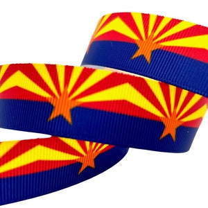 May include: A roll of blue, red, and yellow ribbon with the Arizona state flag printed on it.