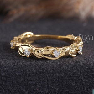 May include: A gold ring featuring a leaf pattern and small diamonds. The ring is set against a dark grey backdrop. The brand name "Aditya Fine Jewelry" is visible in the image.