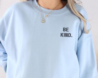May include: A light blue sweatshirt with the text "BE KIND." printed on the front.