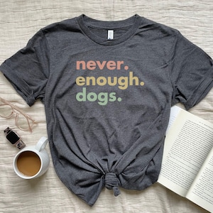 May include: A dark gray t-shirt with the text "never. enough. dogs." printed in a rainbow color scheme.