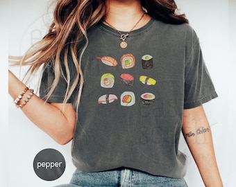 May include: A dark grey cropped t-shirt with a graphic print of various sushi rolls. The shirt has a crew neck and short sleeves.