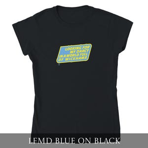 Puede incluir: Camiseta negra con un diseño rectangular azul y amarillo. El diseño dice: "LOOKING FOR MY DARCY IN A WORLD FULL OF WICKHAMS". La camiseta es de cuello redondo.