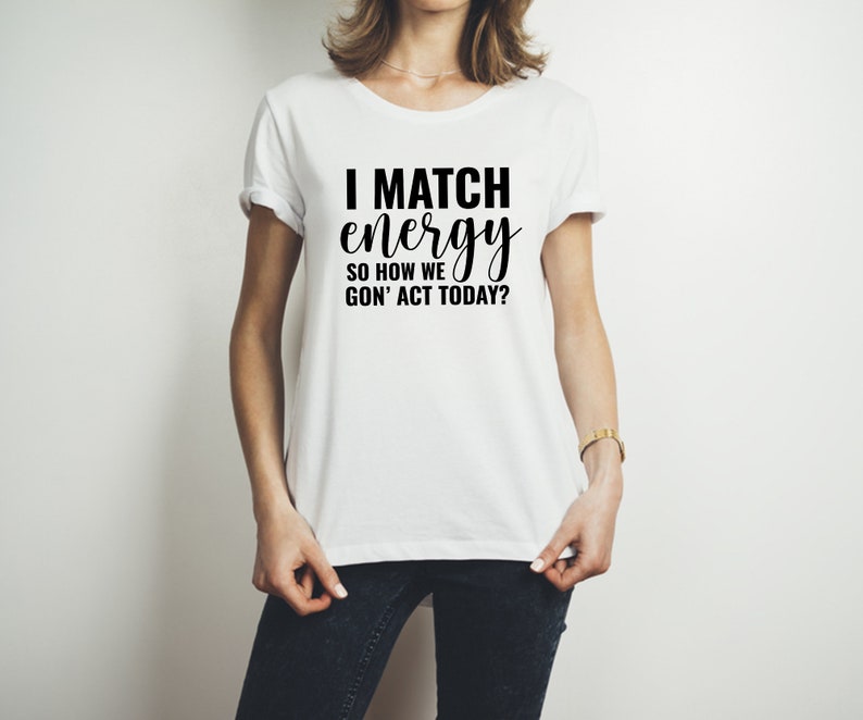 May include: White t-shirt with black text that reads "I match energy so how we gon' act today?"