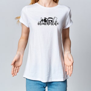 May include: White t-shirt with a black graphic design that says "#teacherlife" and includes a pencil, apple, and ruler.