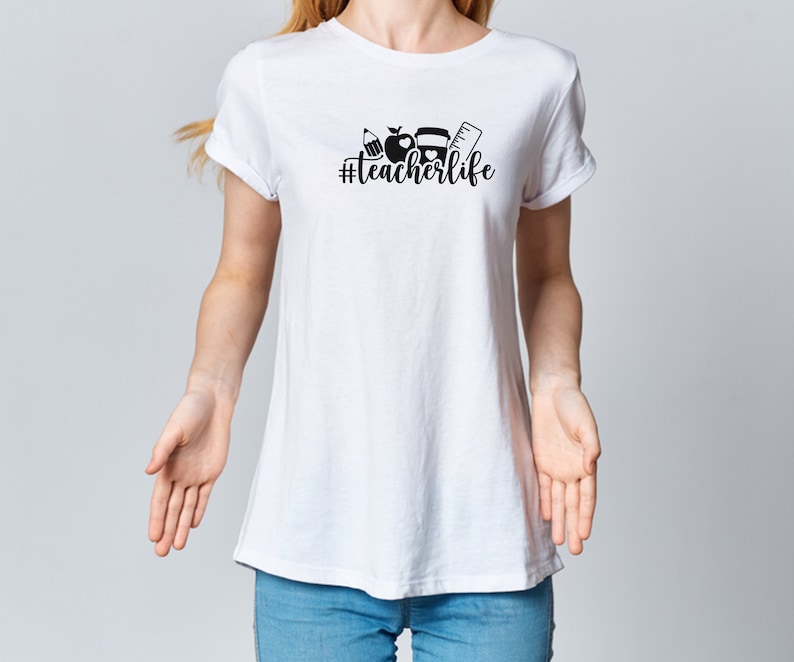 May include: White t-shirt with a black graphic design that says "#teacherlife" and includes a pencil, apple, and ruler.