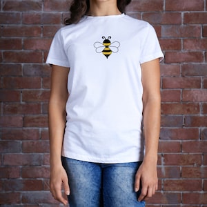 May include: White t-shirt with a black and yellow bee graphic on the front.