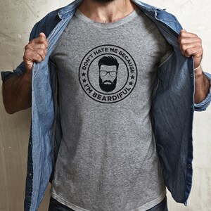 May include: A gray t-shirt with a black and white graphic of a man with a beard. The graphic is in a circle with the text "Don't hate me because I'm beardful".