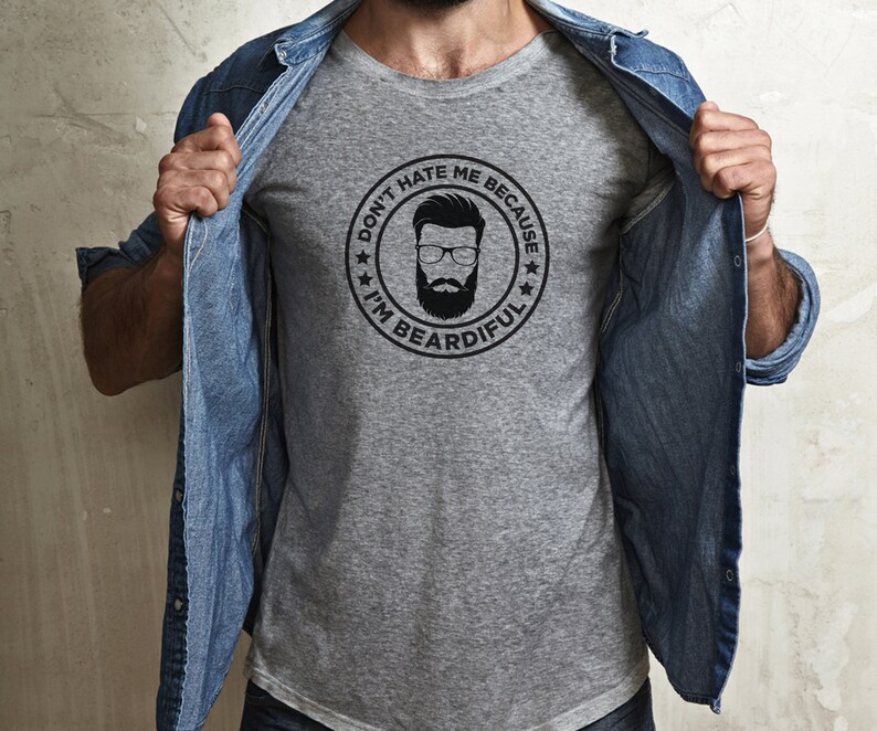 May include: A gray t-shirt with a black and white graphic of a man with a beard. The graphic is in a circle with the text "Don't hate me because I'm beardful".
