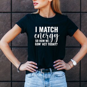 May include: Black t-shirt with white text that reads "I match energy so how we gon' act today?"