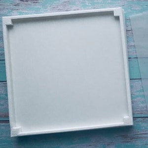 Pode incluir: Uma moldura de tela branca com uma superfície lisa. A moldura é feita de madeira e tem um design simples.