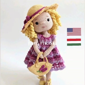 May include: Crocheted doll wearing a purple dress, yellow shoes, and a matching hat. The doll is holding a yellow purse with a floral design. The doll has blonde curly hair and is handmade.