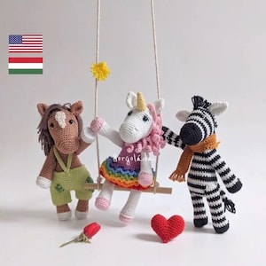 May include: Three crocheted stuffed animals on a swing set. A brown horse, a pink and white unicorn, and a black and white zebra. The unicorn is wearing a rainbow skirt and the zebra is wearing a brown scarf.