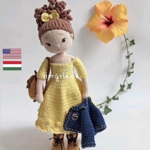 May include: Crocheted doll with brown hair, wearing a yellow dress and a blue denim jacket. The doll is holding a small crocheted bag. The doll is standing on a white background with a yellow hibiscus flower in the background.