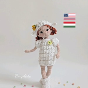 May include: A handmade crochet doll wearing a white dress, hat, and boots. The doll has red hair and is adorned with yellow flowers. Small, colorful flower-shaped beads are scattered around the doll.