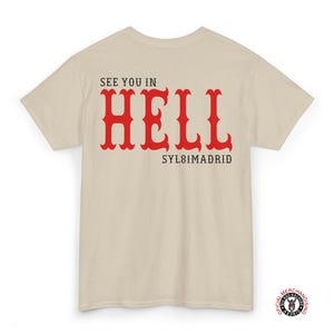 A beige t-shirt with the text "See you in HELL" in red lettering and "SYL8IMADRID" in black lettering on the back.