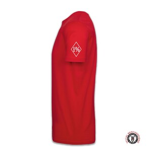 May include: Red short-sleeved t-shirt with a white diamond patch on the sleeve that says "1%".