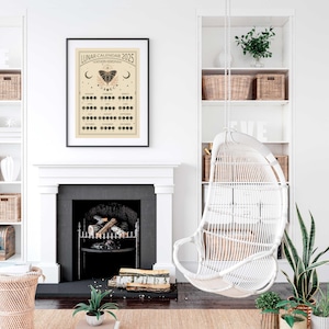May include: A black framed poster with a beige background and the text "Lunar Calendar 2025 Northern Hemisphere". The poster features a calendar with moon phases and a black butterfly illustration.