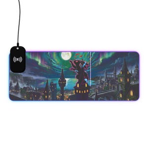 May include: A rectangular LED-lit mouse pad featuring a dark, fantasy-style cityscape at night under a full moon and aurora borealis. A black creature with glowing blue rings stands on a tower. A black wireless charging puck is attached by a cord.