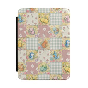 Könnte beinhalten: Eine rechteckige Schutzhülle mit einem Patchwork-Design aus abwechselnden Quadraten. Das Muster besteht aus hellgrünem Vichy-Karo, einfarbigem Altrosa und Blumenfeldern, die mit kleinen, illustrierten Zeichentrickfiguren in verschiedenen Posen versehen sind.