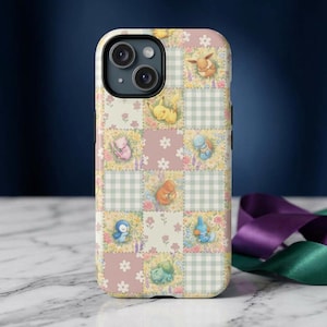 May include: A phone case featuring a patchwork design with various cartoon characters. The case has a light pink, green, and white color scheme with floral and gingham patterns. The characters are in the center of each square.