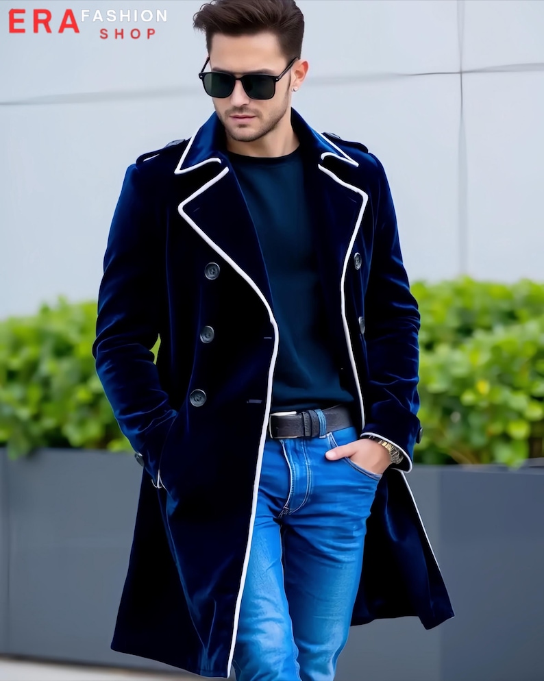 Puede incluir: Un abrigo de terciopelo azul marino con ribetes blancos y botones negros. El abrigo cruzado se lleva con vaqueros azules y un cintur&oacute;n negro. El texto "ERA FASHION SHOP" es visible.