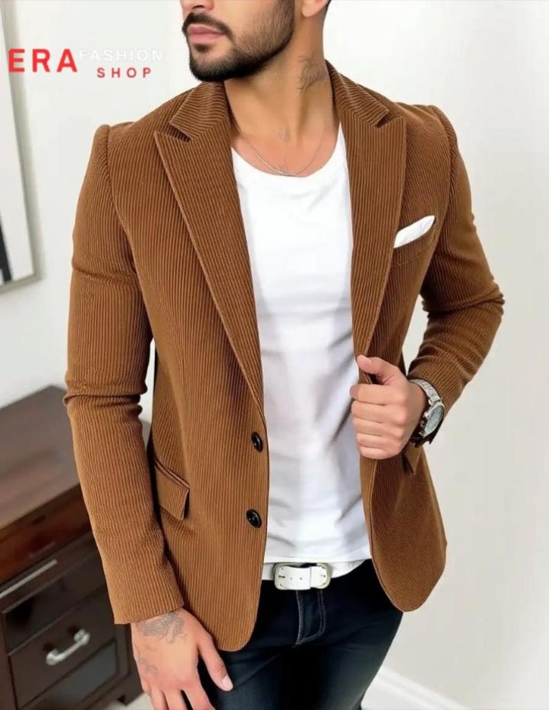 Puede incluir: Una blazer de pana marr&oacute;n con cierre de dos botones, bolsillo en el pecho y solapa con muescas. La blazer se lleva sobre una camiseta blanca y unos vaqueros negros. La imagen incluye el texto "ERA FASHION SHOP".