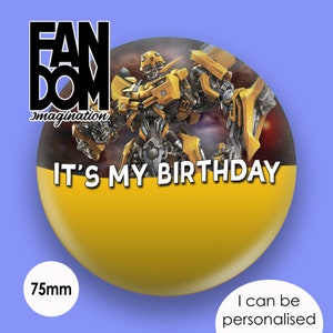 May include: A 75mm round button featuring a picture of Bumblebee from the Transformers film franchise. The text "IT'S MY BIRTHDAY" is printed on the button. The button is from the company "FANDOM imagination".