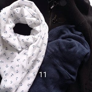 May include: A white scarf with a blue anchor pattern, a navy blue knit cap, and a black coat with toggle closures. The number "11" is visible on the image.