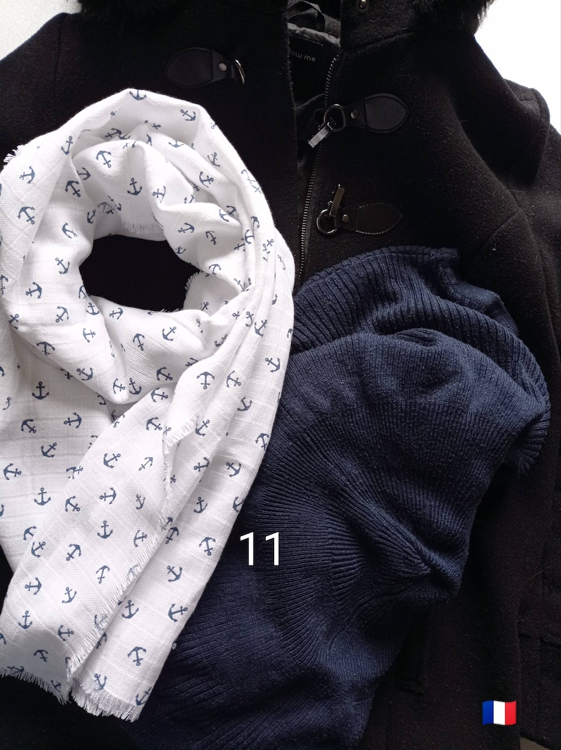 May include: A white scarf with a blue anchor pattern, a navy blue knit cap, and a black coat with toggle closures. The number "11" is visible on the image.