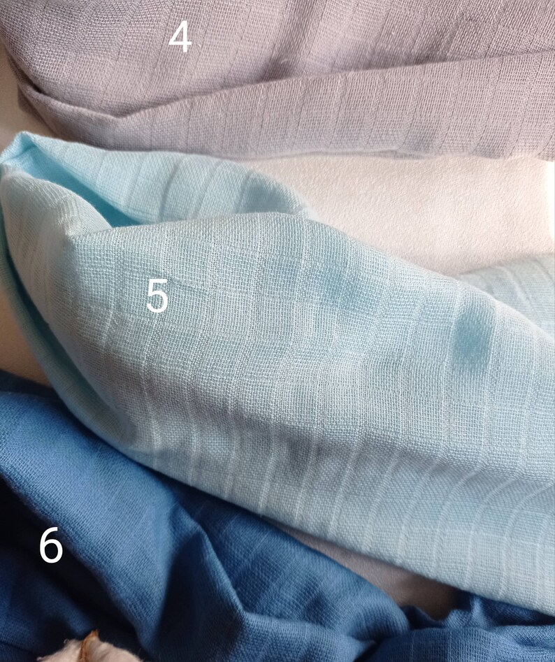 May include: Close-up of folded fabric samples in various shades of blue and gray. The fabrics have a textured, ribbed appearance. The samples are labeled with numbers 4, 5, and 6.