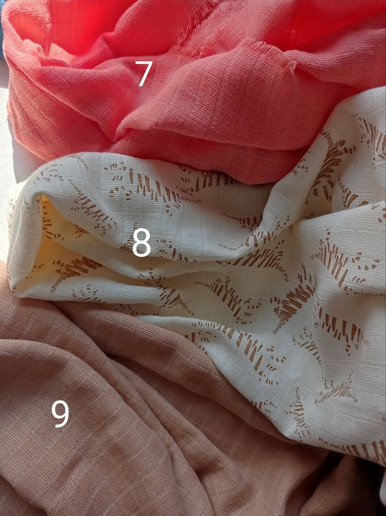 May include: Close-up of three different fabrics. The top fabric is a vibrant coral color, the middle fabric is off-white with a brown pattern, and the bottom fabric is a muted peach color. The fabrics are soft and textured.