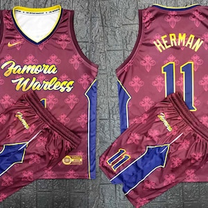 May include: Burgundy basketball jersey with a gold "Zamora Warless" design and matching shorts. The jersey has a navy blue trim and the number "11" on the front and back. The shorts have a navy blue stripe down the side and the word "Zamora" on the side.