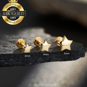 May include: Three gold star-shaped stud earrings in 3mm, 4mm, and 5mm sizes. The earrings are displayed on a dark, textured surface. A gold seal with the text "14K GOLD" and "PREMIUM QUALITY" is in the upper left corner.