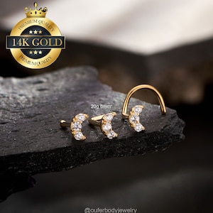 May include: Three gold nose rings with a crescent moon design and clear cubic zirconia stones. The rings are 20 gauge and 6mm in size. The text "20g 6mm" is visible in the image.